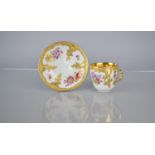 A KPM Porcelain Cup and Saucer decorated with Hand Painted Flowers and Enriched with Gilt Floral