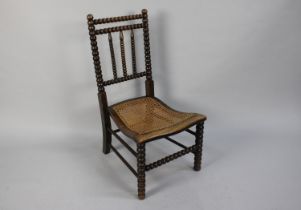 A 19th Century Slipper Chair with Bobbin Turned Back over a Caned Seat, 80cms High