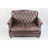 A Button Back Chesterfield Style Two Seater Sofa in Brown Leather Effect, 120cm wide