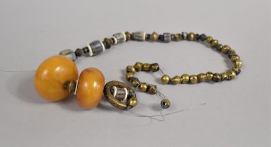 A Far Eastern Type Beaded Necklace Housing Two Large Amber Coloured Beads, Requires Restringing