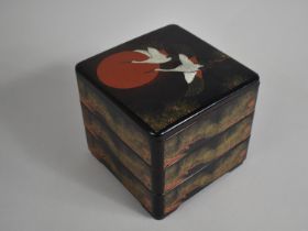 A Modern Oriental Three Tier Lacquered Food Box Decorated with Cranes and Fir Cones, 20cms Square