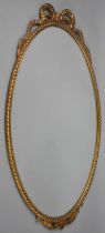 A Mid 20th Century Gilt Metal Framed Oval Wall Mirror with Ribbon Finial, 64x38cms