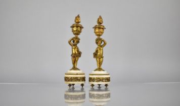 A Pair of French Gilt Bronze and Marble Candlesticks Modelled as Cherubs Supporting Urns having