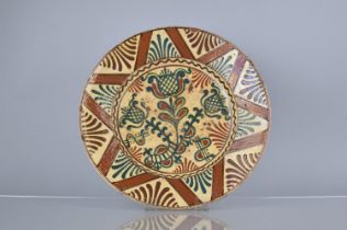 A Terracotta Charger Decorated in Slip Glaze with Thistle Type Plants to Centre and Geometric