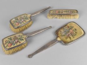 An Embroidered and Silver Mounted Dressing Table Set to Comprise Three Brushes and a Mirror,