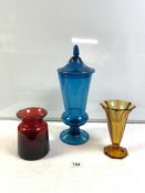 A TALL BLUE GLASS JAR AND COVER, 42 CMS, AND AMBER GLASS VASE AND RED GLASS VASE.