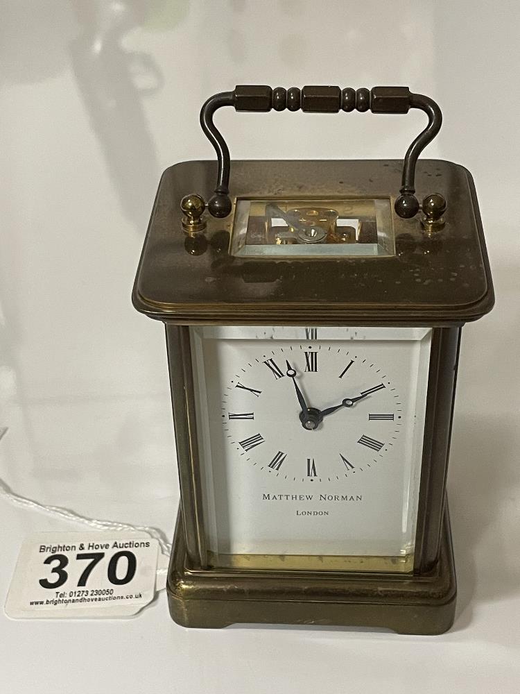 A BRASS CARRIAGE CLOCK WITH WHITE ENAMEL DIAL- MICHAEL NORMAN , LONDON, IN WORKING ORDER WITH KEY.