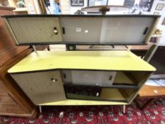 A 1950s/1960s YELLOW AND BLACK MELAMINE SIDEBOARD WITH SLIDING GLASS DOORS AND TWO CUPBOARDS.