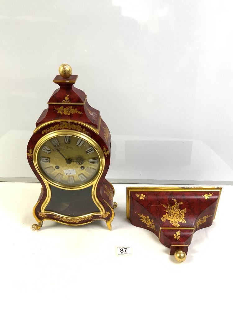 A 20-CENTURY RED AND GOLD LACQUER-SHAPED BRACKET CLOCK BY -LE CASTEL. WITH A SWISS MOVEMENT, 110177.