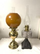 A VICTORIAN IRON-BASED OIL LAMP WITH A GLASS FRONT, AND A LATER BRASS OIL LAMP WITH SHADE.