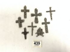 SIX WHITE METAL CROSSES AND A LIONS HEAD PENDANT.