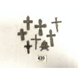 SIX WHITE METAL CROSSES AND A LIONS HEAD PENDANT.