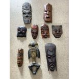 A QUANTITY OF CARVED WOODEN TRIBAL MASKS AND A FIGURE.
