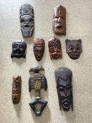 A QUANTITY OF CARVED WOODEN TRIBAL MASKS AND A FIGURE.