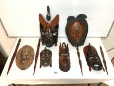 CARVED WOODEN TRIBAL WALL MASKS AND WOODEN KNIVES.