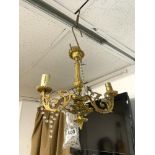 A SMALL ORNATE GILT METAL THREE BRANCH ELECTRIC CHANDELIER WITH GLASS DROPS.