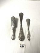 A FRENCH EMBOSSED SILVER-BACKED BRUSH AND TWO EDWARDIAN HALLMARKED SILVER-HANDLED SHOE HORNS.