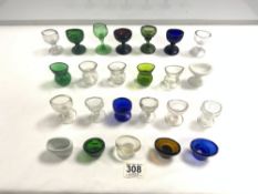 A COLLECTION OF 24 COLOURED AND CLEAR GLASS EYE BATHS.