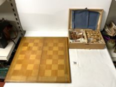 A CARVED WOODEN CHESS SET AND BOARD.