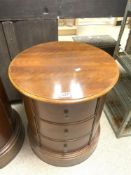 A CYLINDRICAL MAHOGANY THREE DRAWER BEDSIDE CHEST OF DRAWERS, 54 CMS DIAMETER X 60 CMS TALL.