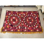 SUZANI FLORAL EMBROIDERED MULTI-COLOURED WALL HANGING ON RED BACKGROUND UZBEKISTAN, 152 X 128 CMS.