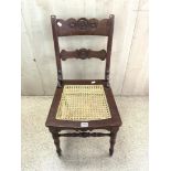 A CARVED WOOD CANE SEAT COLONIAL STYLE CHAIR, WITH ROUNDAL MOTIFS.