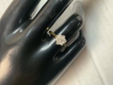 A 750 HALLMARKED GOLD FLOWER HEAD RING SET WITH CLEAR STONES. 3 GMS.