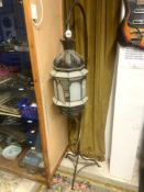 A MOROCCON DESIGN OCTAGONAL GLAZED AND PIERCED METAL HANGING LANTERN, ON IRON STAND, 174 CMS TALL.