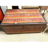 A MOROCCAN KELIM CARPET COVERED THE EASTERN STORAGE TRUNK, WITH LEATHER BORDERS, AND A METAL LOCK.