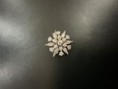 A 1930s MULTI DIAMOND SET FLOWER BROOCH IN WHITE METAL.