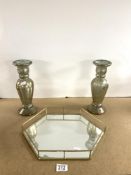 A PAIR OF SILVERED GLASS CANDLESTICKS, 30 CMS, AND A MIRRORED HEXAGONAL TRAY.