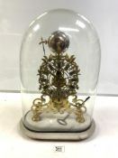 ORNATE BRASS SKELETON CLOCK WITH STEEL CHAPTERED DIAL, ON A WHITE MARBLE BASE, UNDER A GLASS DOME.
