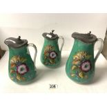 A SET OF THREE VICTORIAN GRADUATING FLORAL DECORATED JUGS WITH PEWTER LIDS, 22CMS TALLEST, A/F.