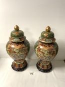 PAIR OF MODERN CHINESE VASES AND COVERS, DECORATED WITH FIGURES ON HORSE BACK, ON WOODEN STANDS,