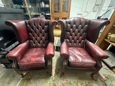 A PAIR OF OX BLOOD BUTTONED LEATHER WING BACK ARMCHAIRS ON CABRIOLE LEGS.