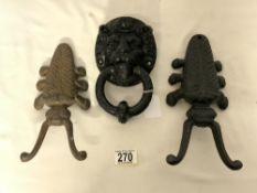 THREE CAST IRON PIECES TWO DOOR STOPS AND A LION FACE DOOR KNOCKER