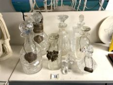 SIX CUT GLASS DECANTERS AND A SCENT BOTTLE, WITH 2 HALLMARKED SILVER LABELS AND OTHERS.