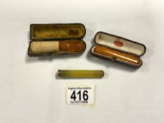 THREE AMBER CIGARETTE HOLDERS, TWO IN LEATHER CASES.
