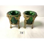 PAIR OF BRASS PUTTI SUPPORT VASES WITH GREEN GLASS LINERS; 15 CMS.