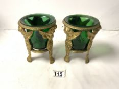 PAIR OF BRASS PUTTI SUPPORT VASES WITH GREEN GLASS LINERS; 15 CMS.