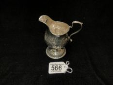 A HALLMARKED GEORGIAN SILVER, LATER EMBOSSED CREAM JUG, RUBBED MARKS; 119 GMS.