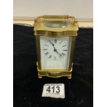 BRASS CARRIAGE CLOCK OF SHAPED OUTLINE WITH WHITE ENAMEL DIAL; W/O; WITH KEY; 12CM