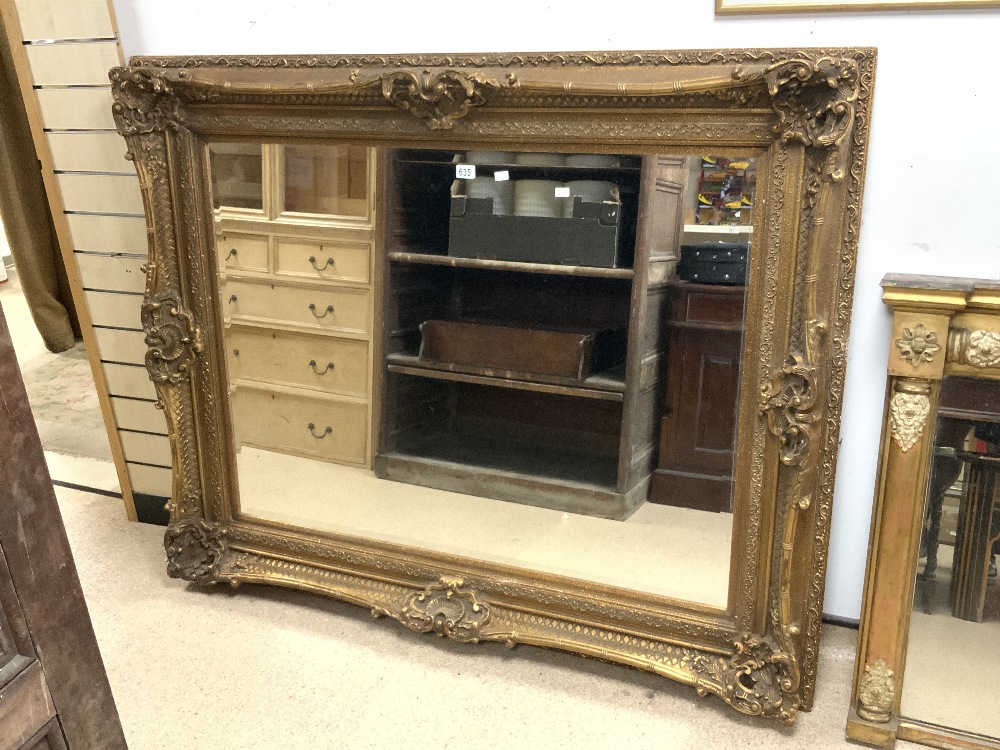 A LARGE MODERN ORNATE GILT FRAMED WALL MIRROR; 158X130 CMS.