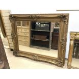 A LARGE MODERN ORNATE GILT FRAMED WALL MIRROR; 158X130 CMS.