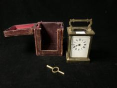 BRASS CARRIAGE CLOCK WITH WHITE ENAMEL DIAL; 11CM WITH A LEATHER OUTER CASE AND KEY