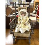 A CHILDS ANTIQUE AMERICAN ROCKING CHAIR WITH A BISQUE HEADED ARMAND MARSEILLE DOLL.