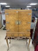 A 1930s BLEACHED WALNUT COCKTAIL CABINET ON CARVED CABRIOLE LEGS, WITH ORNATE METAL HINGES AND LOCK,