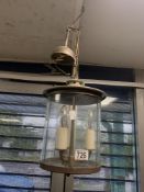 A CYLINDRICAL GLASS AND METAL HANGING LIGHT.