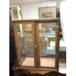 A GLAZED SLIDING DOOR COUNTER TOP DISPLAY CABINET; 75X42X90 CMS.