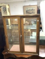 A GLAZED SLIDING DOOR COUNTER TOP DISPLAY CABINET; 75X42X90 CMS.